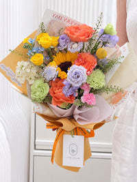 Full view of Chasing Dreams colourful graduation flower bouquet with sunflowers and roses, wrapped in orange and cream paper with satin ribbon.