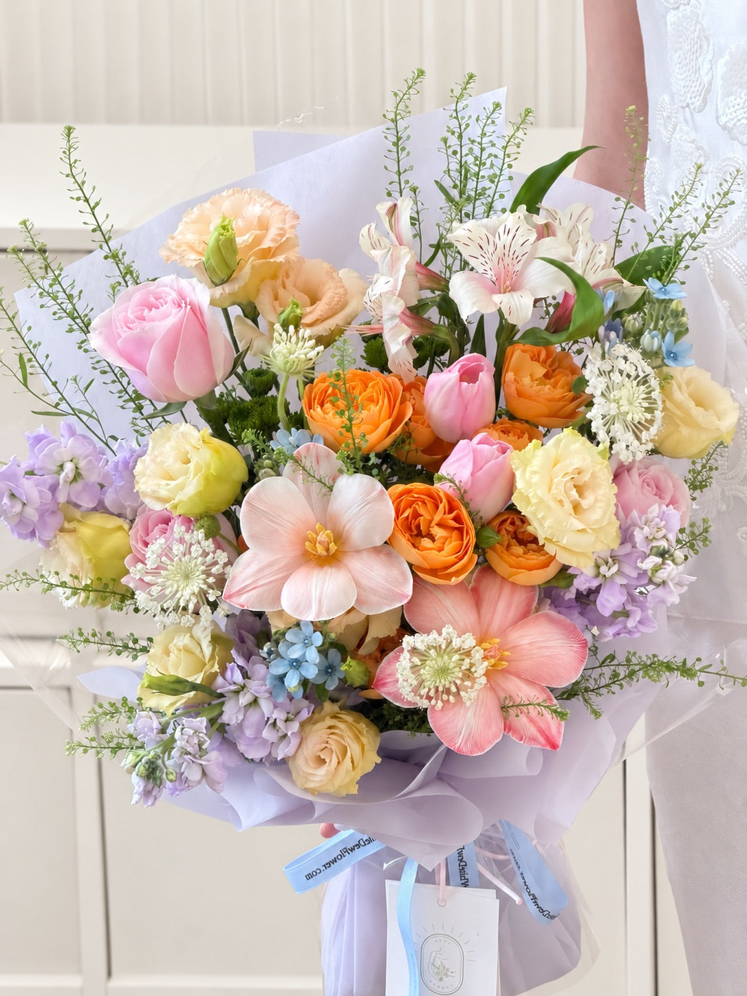 Pastel mixed flower bouquet featuring Holland tulips, pink roses, champagne lisianthus and delicate spring flowers