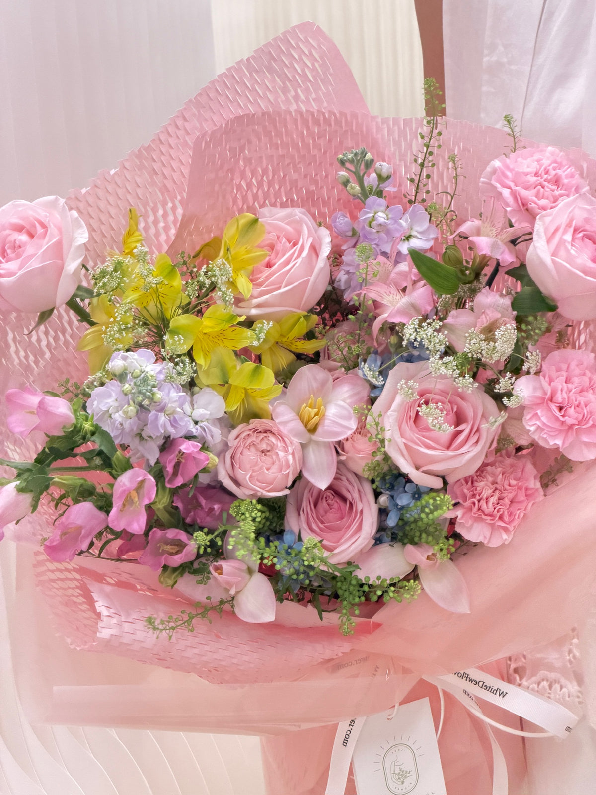 Close-up of pink roses, carnations, yellow alstroemeria and lavender flowers in a pastel bouquet