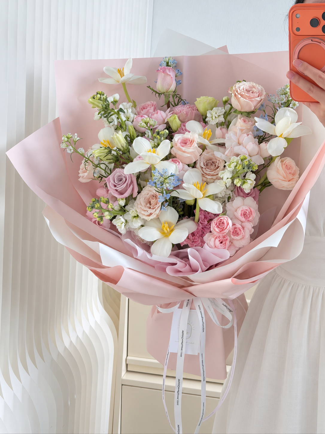 Luxury blush pink rose and white tulip bouquet with blue delphiniums, wrapped in elegant pastel pink paper