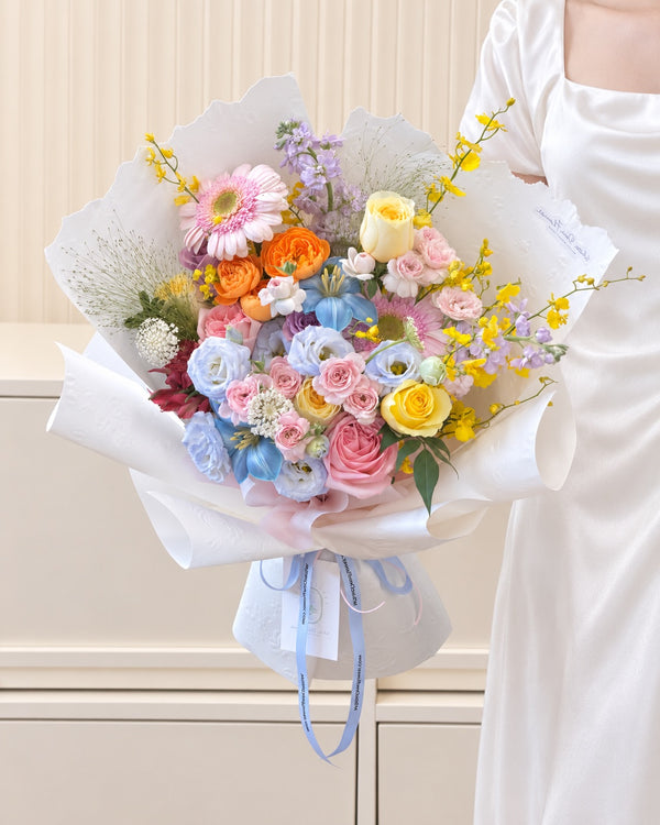 Colourful Garden bouquet with pink gerberas, yellow roses, orange spray roses and blue lisianthus in white wrapping