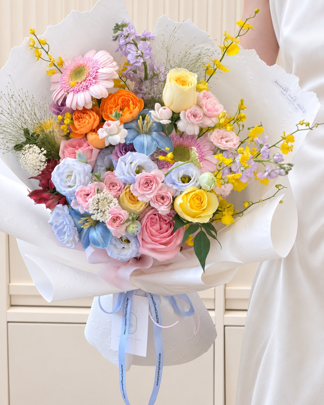 Close-up of Colourful Garden bouquet with pink gerbera daisies, orange spray roses, blue lisianthus and yellow Oncidium orchids