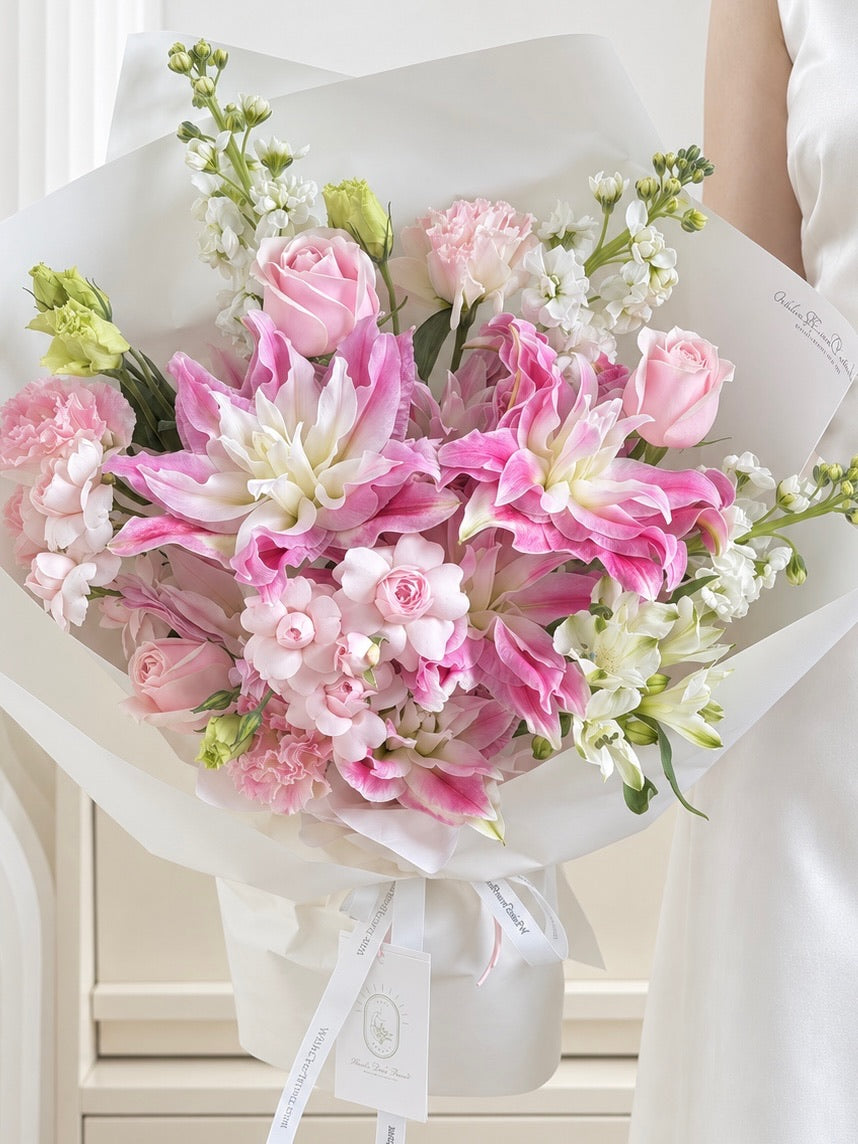 Blushing Lily Bouquet with pink double-petaled lilies, Pink Snow Mountain roses and white Matthiola in elegant white wrapping