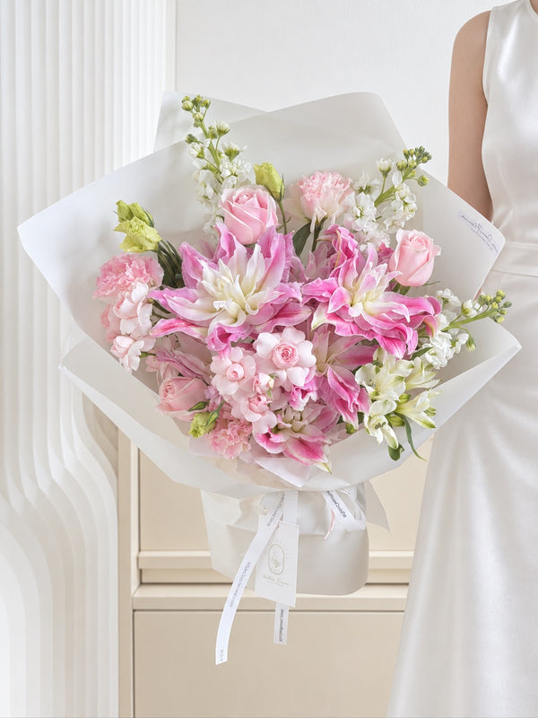 Elegant pink double lily and rose bouquet held by a woman in a white dress, perfect for romantic gifting in Singapore