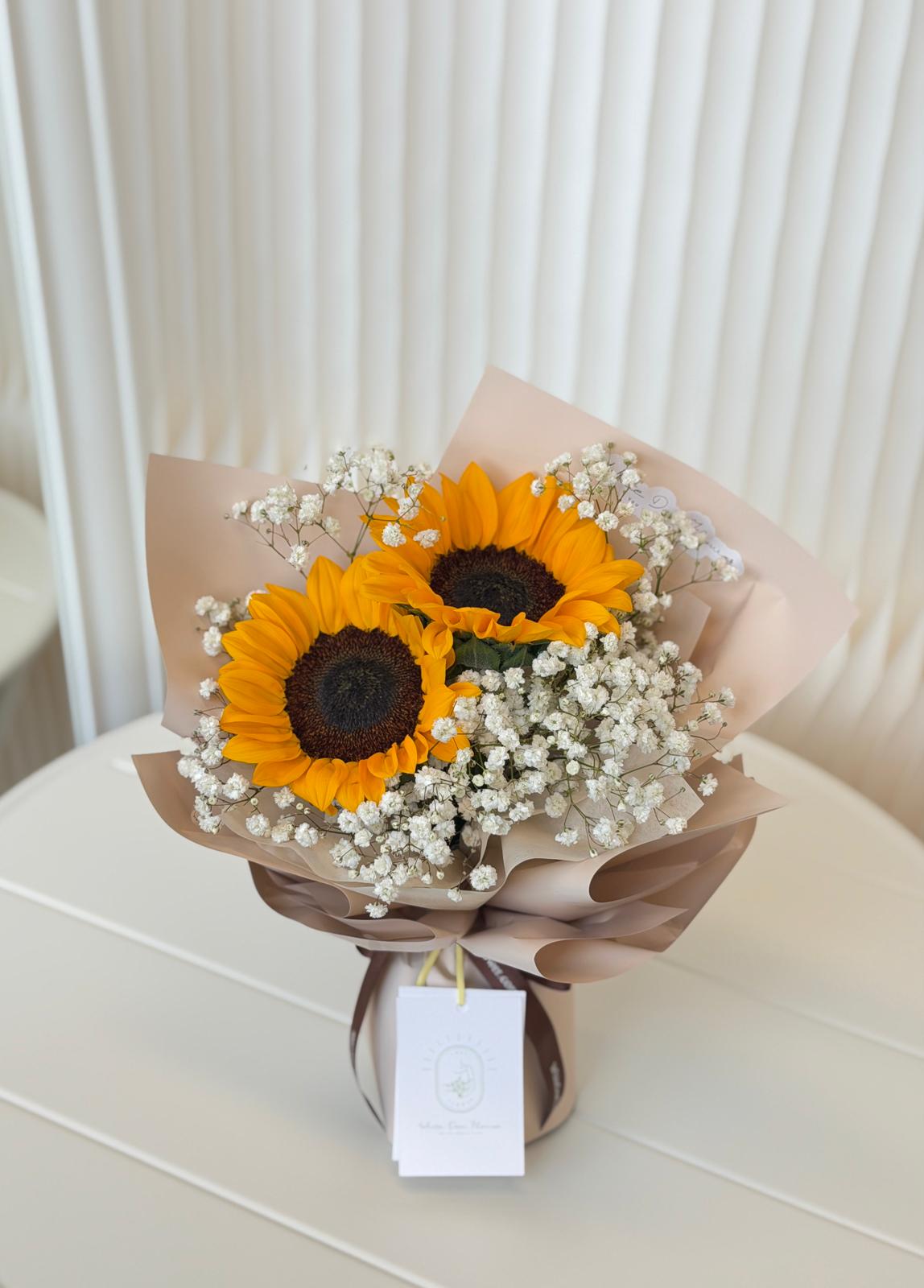 Graduation sunflower bouquet with baby’s breath in soft neutral wrapping, symbolising new beginnings and joy
